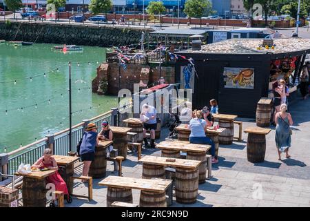 Folkestone, Vereinigtes Königreich - 9. Juli 2023: Menschen sitzen beim Essen von Fish and Chips vor dem Fish and Chips Shop The Hatch Stockfoto