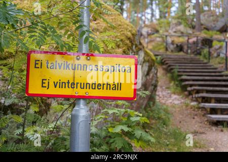 Gelbes Schild mit der Aufschrift „Keine Wartung im Winter“ auf Finnisch und Schwedisch neben einer hölzernen Außentreppe Stockfoto