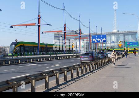 Poznan, Polen - 21. April 2023: Gelenkte niederstöckige grüne Straßenbahn an einer Straßenbahnstelle in der Nähe des Busbahnhofs in Poznan. Stockfoto