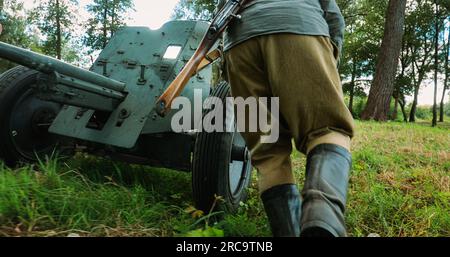 Eine Gruppe von Re-Enactors, die als russische Rote Armee verkleidet waren, die Infanterie-Soldaten des Zweiten Weltkriegs werden die sowjetische 45mm Anti-Panzer-Waffe in Kampfposition bringen Stockfoto