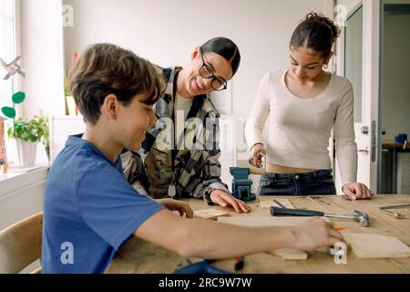 Lächelnder junger Lehrer mit männlichen und weiblichen Schülern im Schreinerkurs Stockfoto