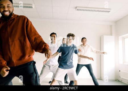 Lächelnder Junge, der mit Freunden tanzen lernt, und Lehrer im Studio an der Highschool Stockfoto