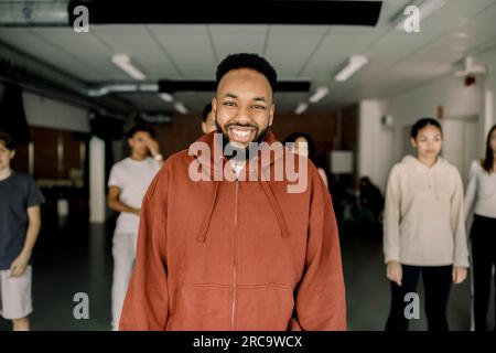 Porträt eines glücklichen Lehrers mit Schülern im Hintergrund im Tanzstudio Stockfoto