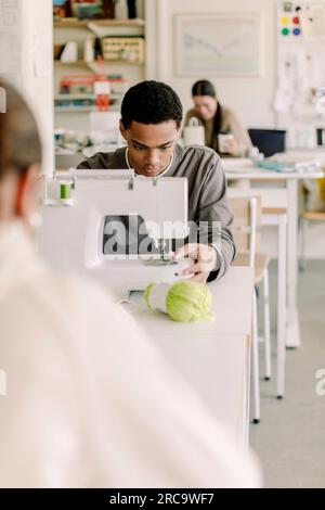 Konzentrierter männlicher Teenager-Schüler, der Stickerei im Kunstunterricht an der Highschool lernt Stockfoto