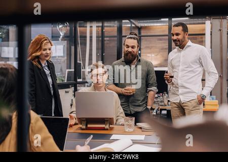 Multiethnische Geschäftskollegen diskutieren über ein Notebook, während sie ihre Strategie im Büro planen Stockfoto