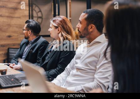 Geschäftskollegen sitzen während der Besprechung im Konferenzraum zusammen Stockfoto