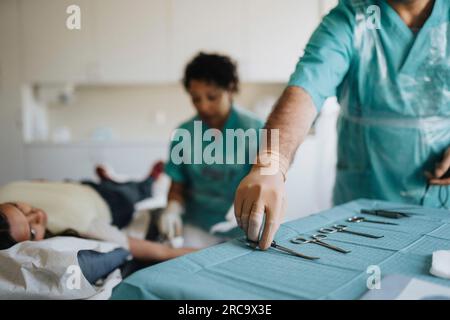 Männlicher Chirurg, der chirurgische Geräte auf dem Tisch im Krankenhaus anlegt Stockfoto