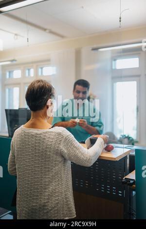 Seniorin meldet sich an der Rezeption im Krankenhaus an Stockfoto
