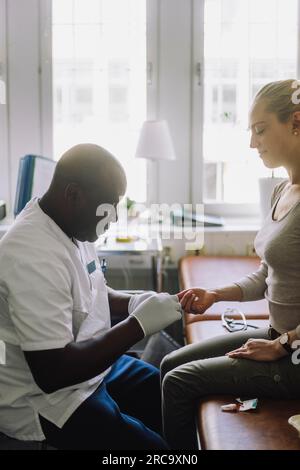 Seitenansicht des männlichen Arztes zur Kontrolle des Blutzuckerspiegels des Klinikpatienten Stockfoto