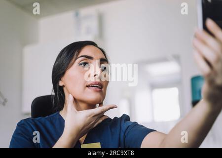 Eine Krankenschwester, die im Krankenhaus eine Online-Beratung über Smartphone durchführt Stockfoto