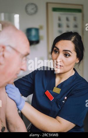 Krankenschwester, die mit dem älteren Patienten im Krankenhaus spricht Stockfoto