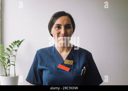Portrait einer lächelnden selbstbewussten Krankenschwester an der Wand im Krankenhaus Stockfoto