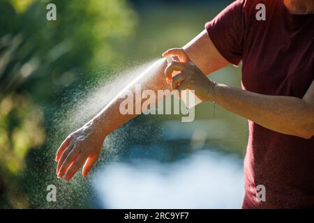 Frau, die im Freien Insektenschutzmittel auf ihren Arm aufträgt. Hautschutz gegen Zecken- und Mückenstich Stockfoto