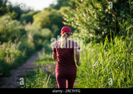Eine Frau, die in der Natur läuft. Sport- und Cardio-Training im Freien im Sommer Stockfoto