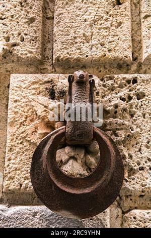 Rostige und verwitterte Pferdeanhänger aus Metall an einer Wand eines alten Gebäudes in Siena, Toskana, Italien. Stockfoto