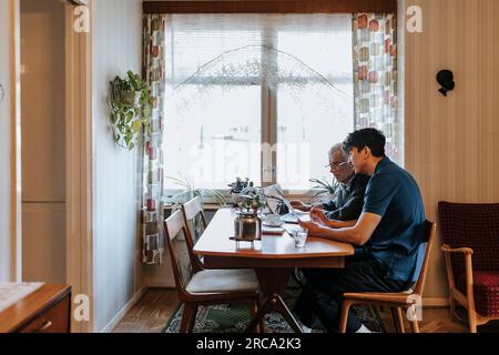 Seitenansicht des pflegenden Mannes über ärztliche Berichte mit Seniorenmenschen zu Hause Stockfoto