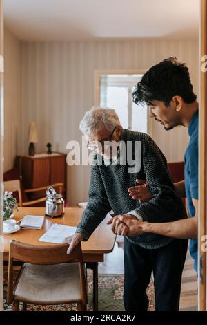 Männliche Pflegehelferin, die Seniorin beim Laufen zu Hause hilft Stockfoto