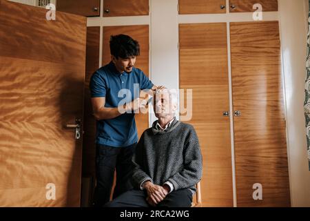 Männlicher Gesundheitshelfer, der sich um Senioren kümmert, die zu Hause sitzen Stockfoto