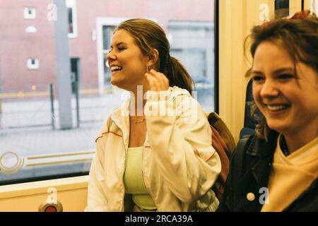 Glückliche Frau, die lacht, während sie mit einem Freund im Zug reist Stockfoto