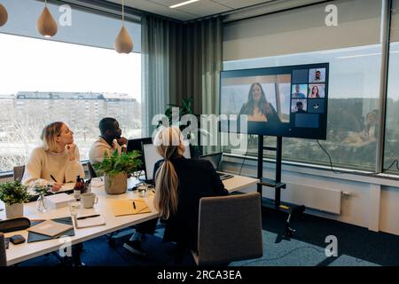 Geschäftsfrau, die Videoanrufe mit männlichen und weiblichen Kollegen im Konferenzraum im Büro führt Stockfoto