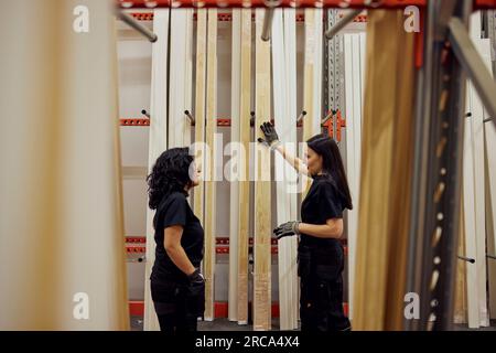 Multirassische weibliche Kollegen, die über Bretter in der Holzindustrie diskutieren Stockfoto
