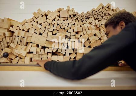 Junge Zimmerlerin, die Bretter auf Regalen in der Industrie anlegt Stockfoto