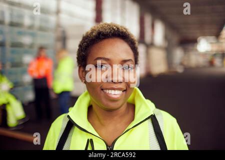 Porträt einer lächelnden jungen Arbeiterin in reflektierender Kleidung in der Industrie Stockfoto