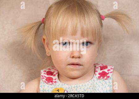 Porträt eines 2-jährigen Mädchens, das verdächtig in die Kamera schaut. Stockfoto