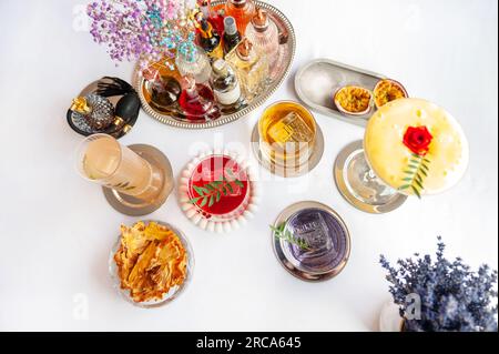 Fünf farbenfrohe Sommercocktails in Gläsern auf einem weißen Tisch. Auswahl an frischen Sommergetränken. Orange- und rote Sangria-Cocktails, Orangen-Punsch-Cocktails, Stockfoto