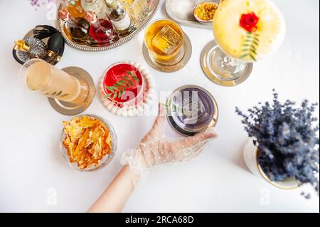 Fünf farbenfrohe Sommercocktails in Gläsern auf einem weißen Tisch. Auswahl an frischen Sommergetränken. Orange- und rote Sangria-Cocktails, Orangen-Punsch-Cocktails, Stockfoto