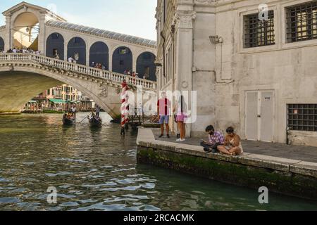 Touristen am Gondelpier zwischen der Rialtobrücke und dem Palazzo dei Camerlenghi auf dem Canale Grande im Sommer, Venedig, Veneto, Italien Stockfoto