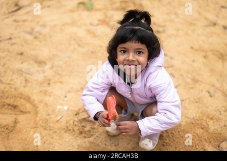 Ein kleines Mädchen hat viel Spaß beim Spielen im Schlamm. Sie lacht und lächelt, und sie sieht aus, als hätte sie die beste Zeit ihres Lebens. Stockfoto