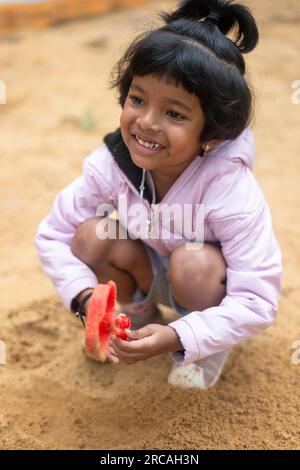 Ein kleines Mädchen hat viel Spaß beim Spielen im Schlamm. Sie ist voller Schlamm Stockfoto