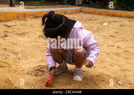 Ein kleines Mädchen hat viel Spaß beim Spielen im Schlamm Stockfoto