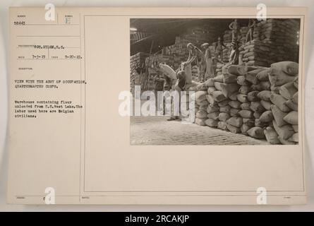 Lagerhaus der Besatzungsarmee, Quartermaster Corps, das Mehl von der S.S. lagert West Lake. Man sieht belgische Zivilisten, die die Fracht handhaben. Foto aufgenommen am 20. Mai 1919. Dieses Bild trägt die Nummer 58443 in der TDMay2019 Kollektion und wurde von S.C. Ryden aufgenommen. Stockfoto