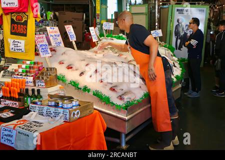 Berühmt für Fisch, der die Käufe von Kunden wirft, bevor er den Pike Place Fish Market Seattle Washington State USA einpackt Stockfoto