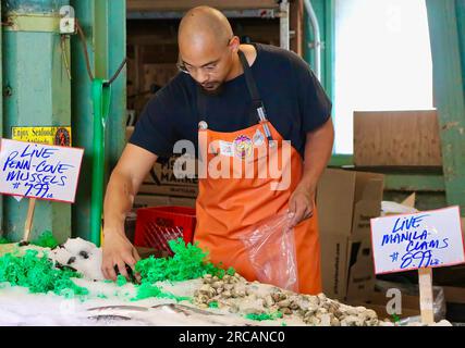 Berühmt für Fisch, der die Käufe von Kunden wirft, bevor er den Pike Place Fish Market Seattle Washington State USA einpackt Stockfoto