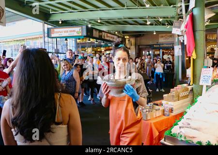 Berühmt für Fisch, der die Käufe von Kunden wirft, bevor er den Pike Place Fish Market Seattle Washington State USA einpackt Stockfoto