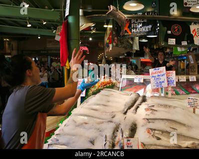 Berühmt für Fisch, der die Käufe von Kunden wirft, bevor er den Pike Place Fish Market Seattle Washington State USA einpackt Stockfoto