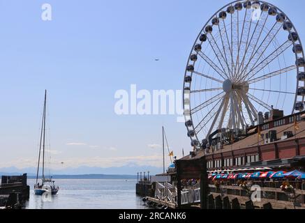 Seattle Great Wheel Ferris Rad über Wasser gebaut mit einer Touryacht Abfahrt und entferntem Paraglider Pier 57 Elliott Bay Seattle Washington State USA Stockfoto