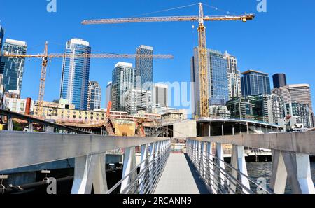 Skyline der Stadt mit einem Bauprojekt und Turmkränen entlang der Uferpromenade von einem schwimmenden Pier 62 Seattle Washington State USA Stockfoto