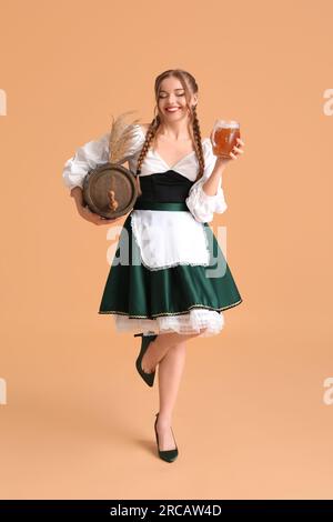 Wunderschöne Oktoberfest-Kellnerin mit Bier und Fass auf beigefarbenem Hintergrund Stockfoto