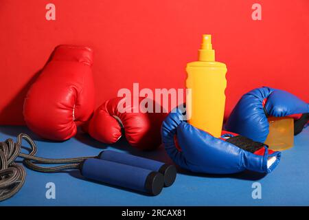 Eine Flasche Sonnencreme, ein Seil und Boxhandschuhe auf farbigem Hintergrund Stockfoto