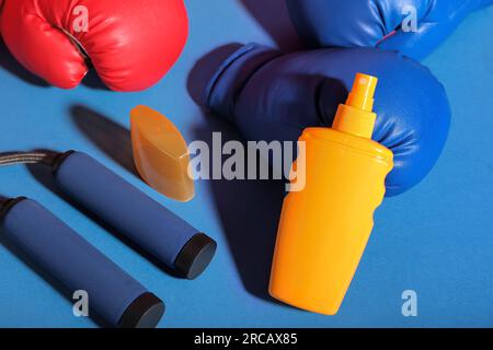 Eine Flasche Sonnencreme, ein Seil und Boxhandschuhe auf farbigem Hintergrund Stockfoto