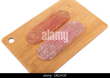 In Scheiben geschnittene Chorizo- und Cervelatwürste auf einem Schneidebrett auf weißem Hintergrund. Speicherplatz kopieren. Stockfoto