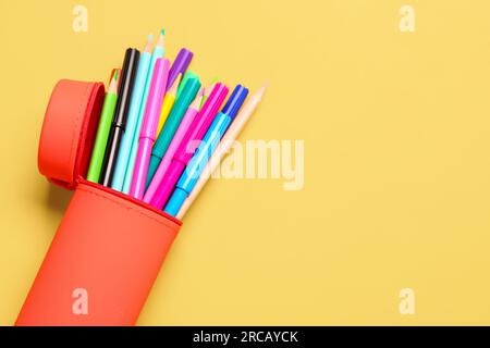 Tasche mit bunten Bleistiften und Markern auf orangefarbenem Hintergrund Stockfoto