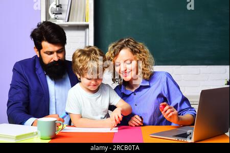 Lehrer lernen und helfen Kindern im Klassenzimmer beim Wissensstudium. Grundschullehrer mit süßem Schüler, der Hausaufgaben im Klassenzimmer macht Stockfoto