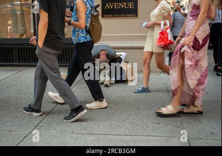 Am Mittwoch, den 5. Juli 2023, gehen die Leute an einem Obdachlosen vorbei, der auf dem Bürgersteig im Flatiron-Viertel in New York bettelt. (© Richard B. Levine) Stockfoto