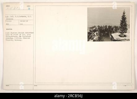 Sgt. 1cl. H.D. Lothers, S.C. steht neben einem Weihnachtsbaum, während die Band am Weihnachtsmorgen 1918 vor dem 3. Armeehauptquartier spielt. Dieses Foto wurde in Coblenz, Rheinpreußen, aufgenommen. Stockfoto