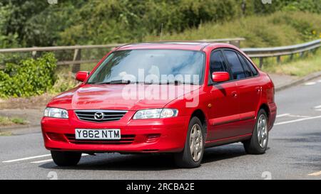 Milton Keynes, Großbritannien - Juli 13. 2023: 2001 rotes MAZDA 626 Auto, das auf einer englischen Straße fährt Stockfoto